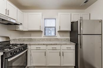 A kitchen with white cabinets and a black refrigerator